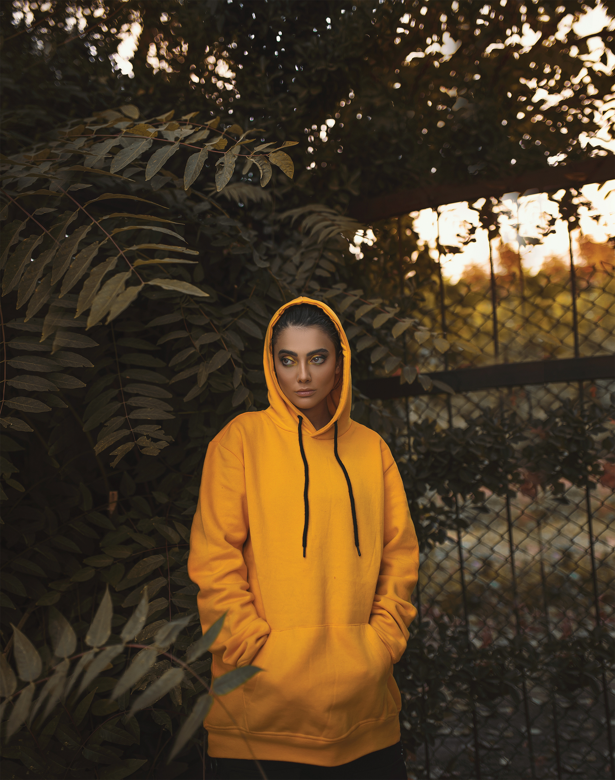 Woman in Yellow Hoodie Standing next to Plant